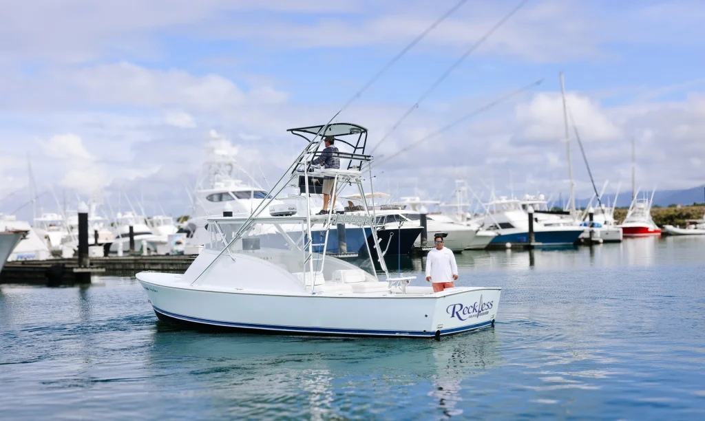 Reckless Sport Fishing boat docked at the marina in Quepos, Costa Rica, with crew members onboard, offering professional sport fishing charters in the Pacific Ocean.
